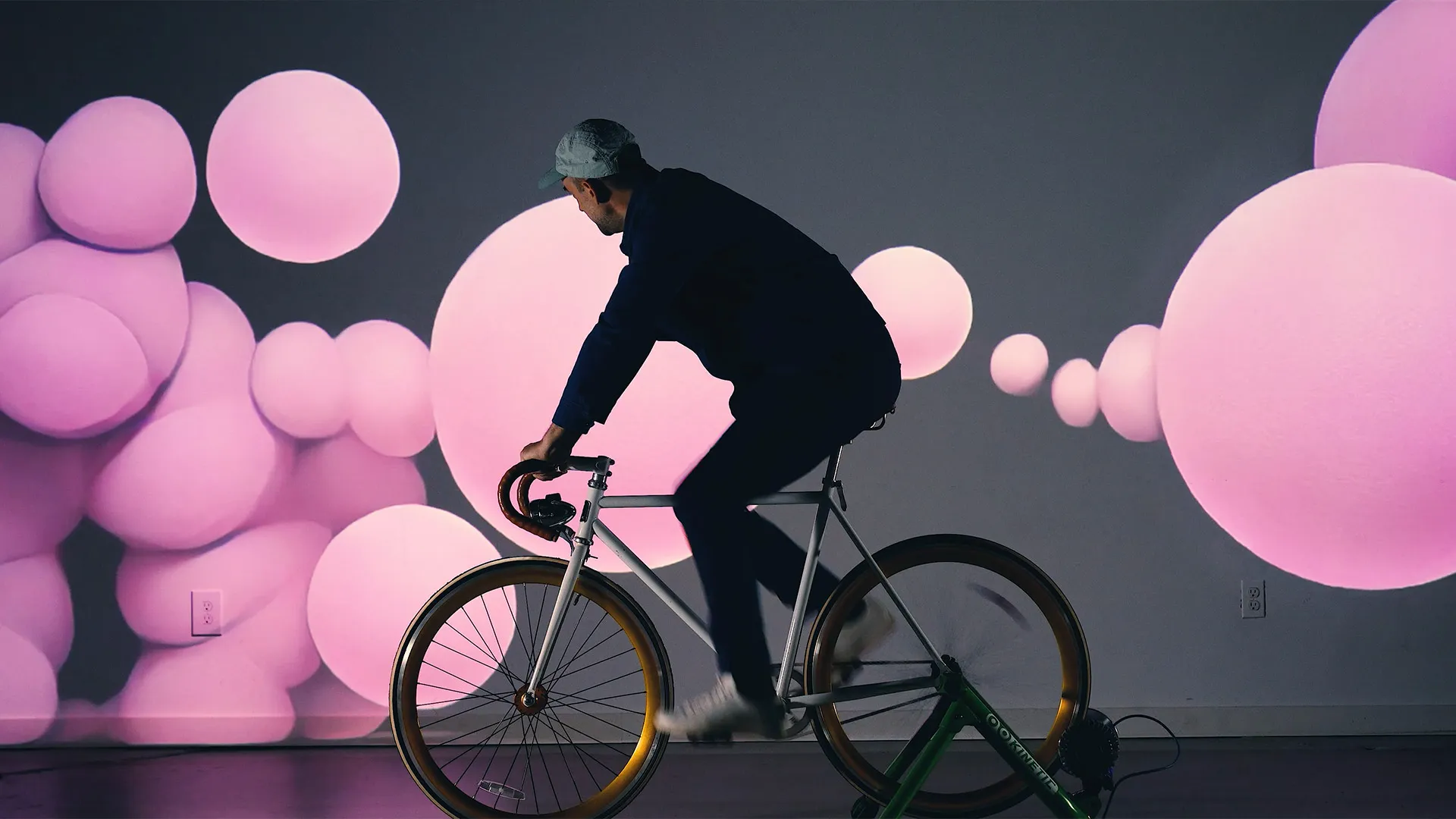 Interactive art installation featuring a stationary bike connected to a digital screen with ai generated abstract, colorful visuals that respond to the cyclist's movements, creating a dynamic and immersive experience