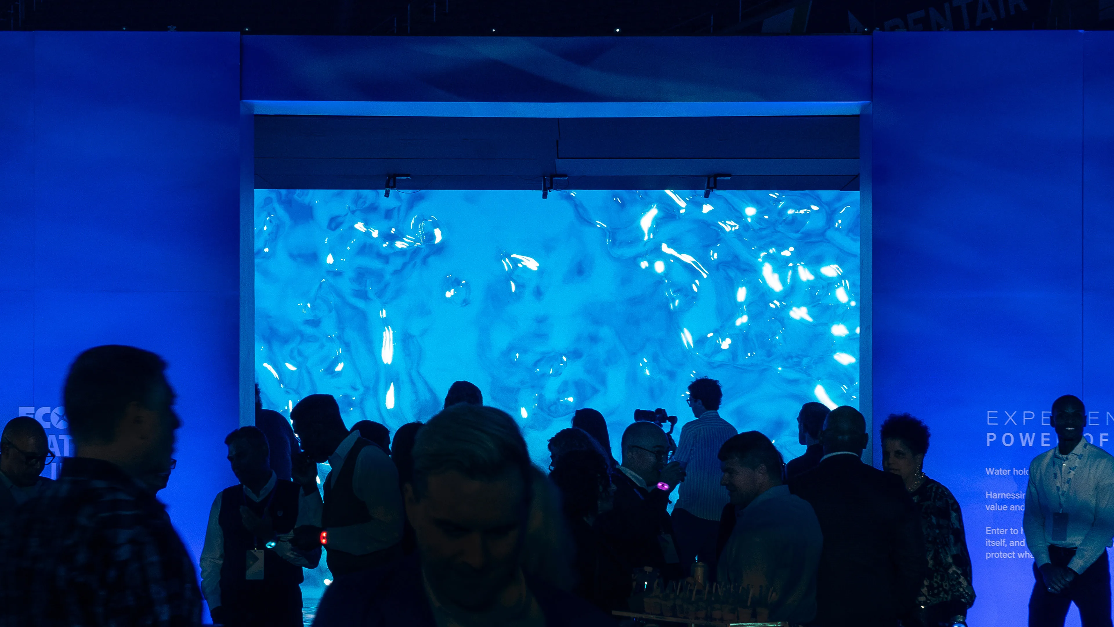 A crowded entrance way into an interactive installation. The installation features dynamic water fluid simulations