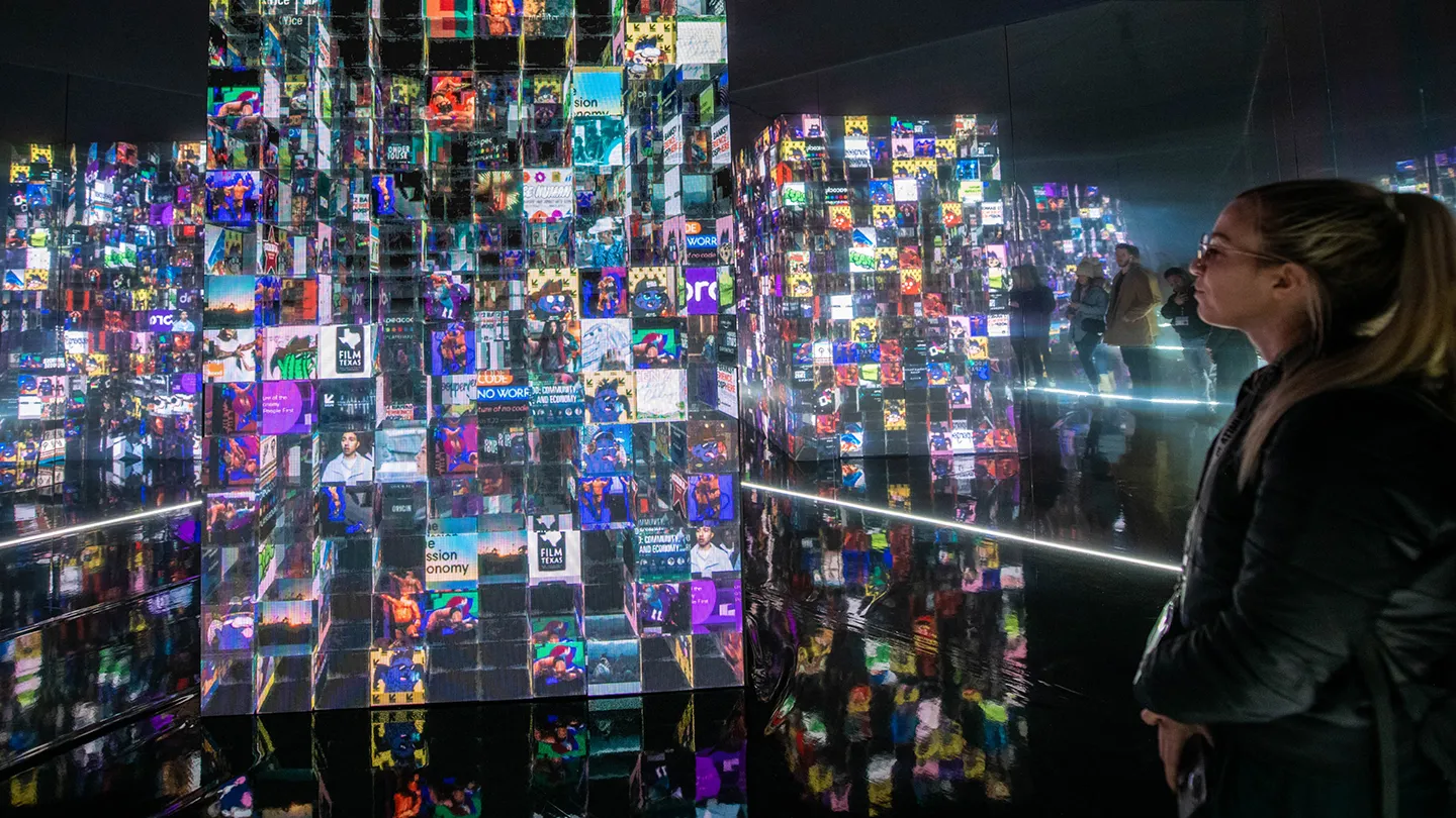 interactive art installation, infinity mirror room, woman looking at led screen cube with many images on it